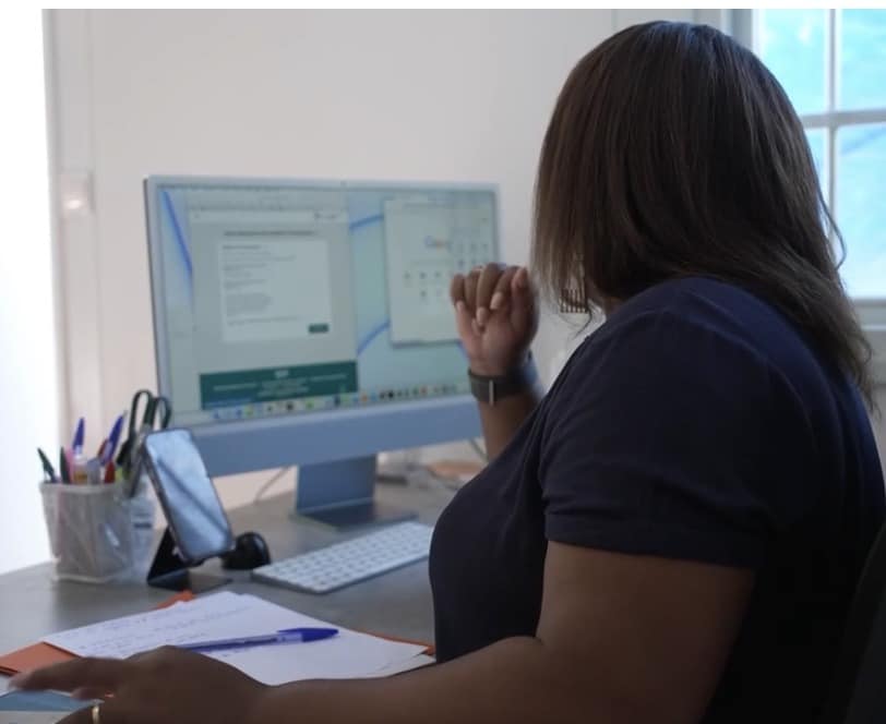 Elaïka de dos devant son ordinateur dans son espace de travail en Guadeloupe